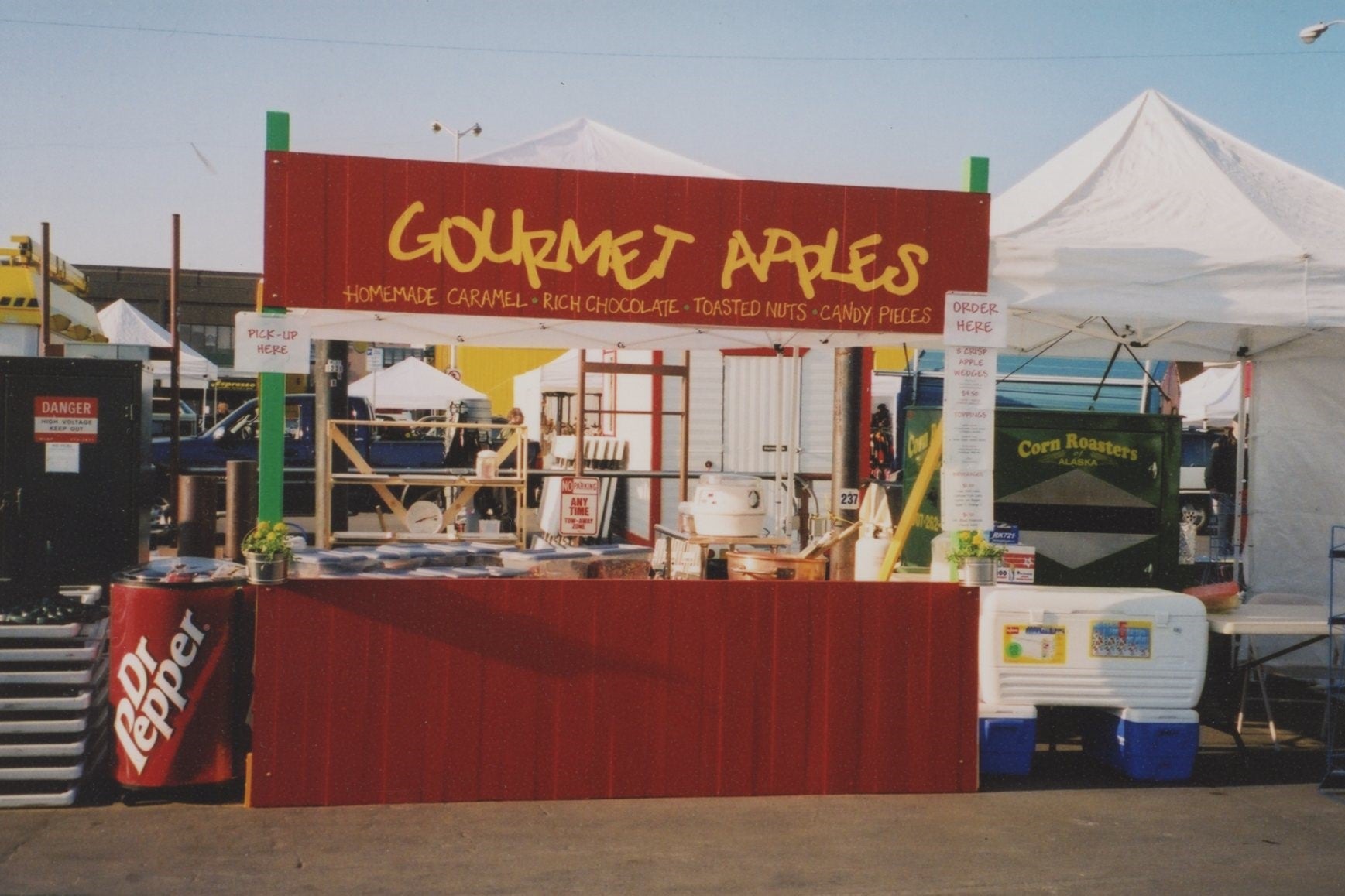 Red Saturday Market Booth with the words "Gourmet Apples: Homemade Caramel, Rich Chocolate, Toasted Nuts, Candy Pieces" across the top.